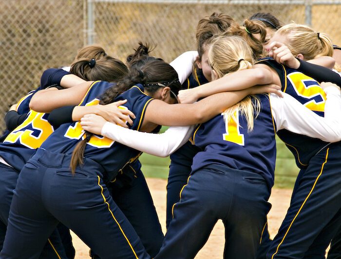 Softball team huddle before the start of a softball game in color. 