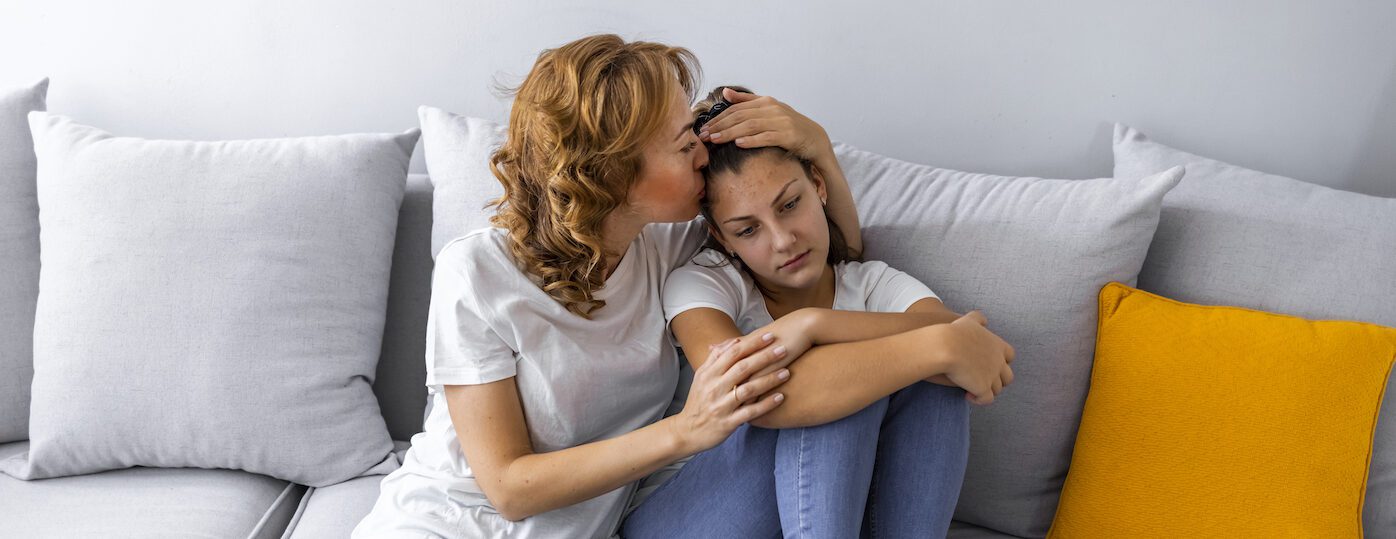 Mother Talking With Unhappy Teenage Daughter On Sofa